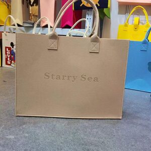 beige felt tote bag with leather handles and starry sea embossed branding