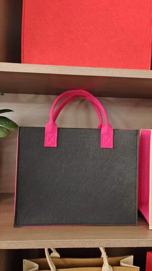 charcoal gray felt bag with hot pink handles and diamond stitched attachments
